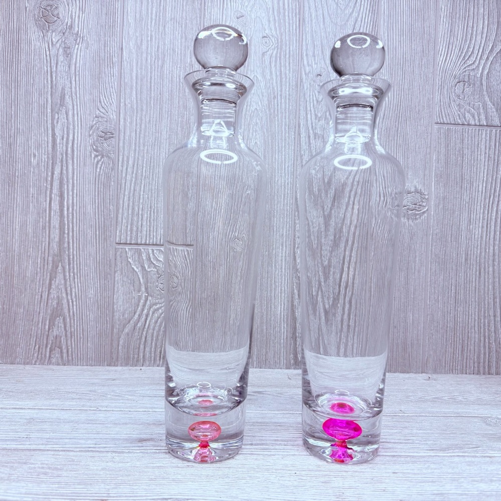 Two tall clear glass decanters with colorful pink / red bubbles bar wear decants